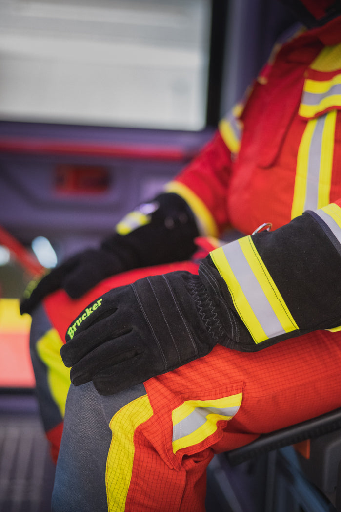 Feuerwehrmann sitzt im Einsatzfahrzeug und legt die Hände mit den Einsatzhandschuhen S Black auf die Knie