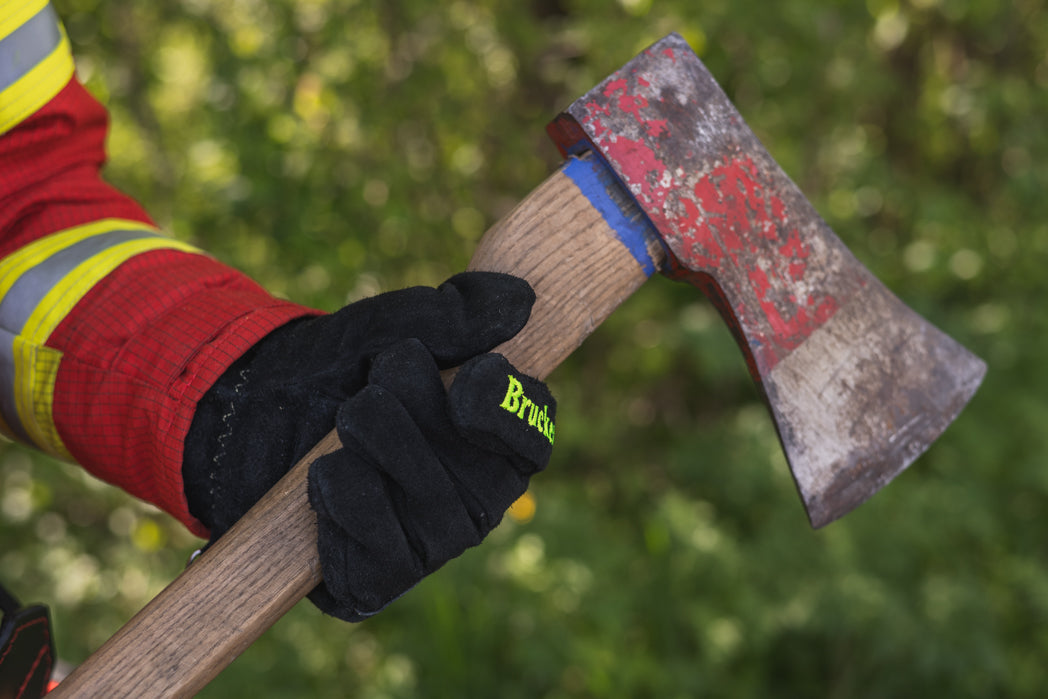 Person hält mit links mit Feuerwehrhandschuhen Black eine Axt unterhalb des Axtkopfes