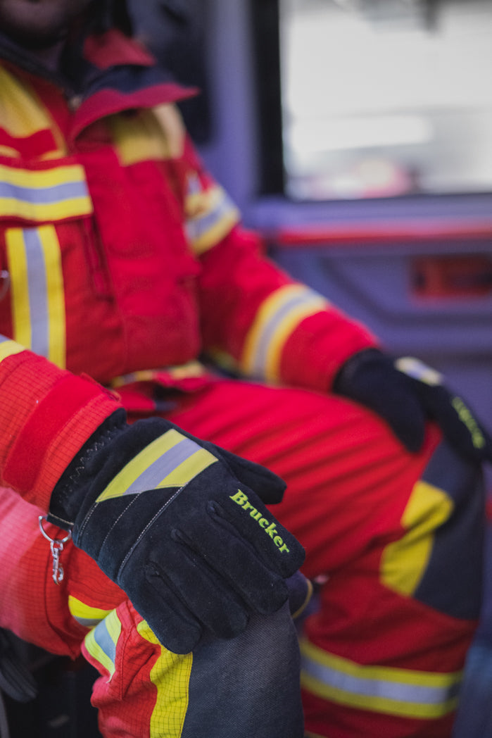Feuerwehrmann sitzt im Einsatzfahrzeug und legt die Hände mit den Einsatzhandschuhen Black auf die Knie